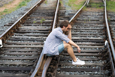 Side view of man sitting on railroad track