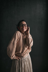 Portrait of a smiling young woman standing against wall