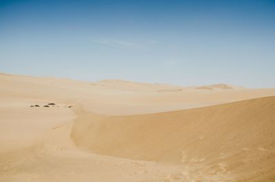 Sand dunes in desert against clear sky