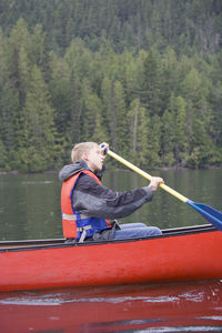 Side view of teenage boy canoeing on lake