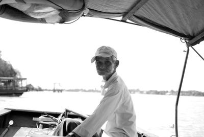 Man sitting on boat at harbor against clear sky