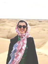 Portrait of smiling young woman in headscarf standing at desert
