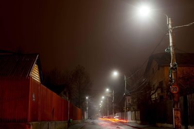 Illuminated street against sky at night