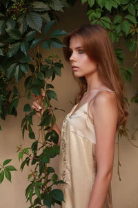 Thoughtful beautiful female model standing against plants