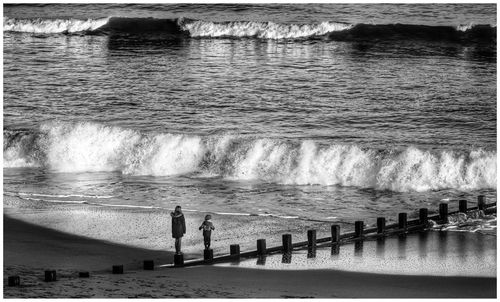 High angle view of mother and child standing on wooden posts at beach