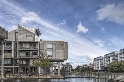 Buildings by river against sky