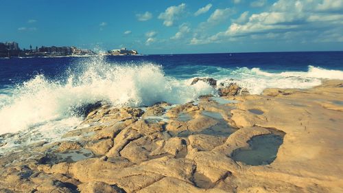 Waves splashing on shore against sky