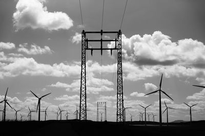 Low angle view of windmills on field against sky