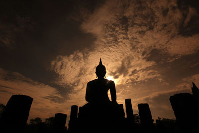 Low angle view of silhouette buddha statue against sky during sunset