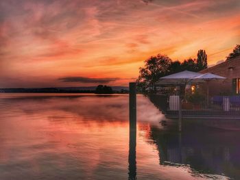 Swimming pool by lake against sky during sunset