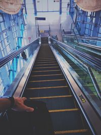 Cropped hand of man holding bag on escalator