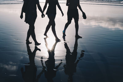 Low section of silhouette people walking on water