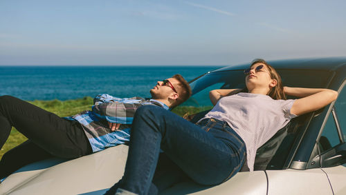 Young couple lying on car at beach