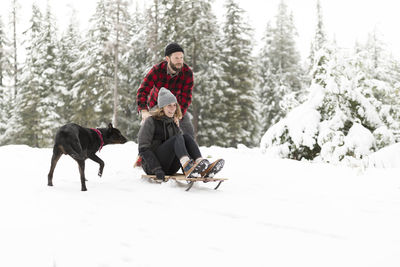 Man pushing woman on a sled in the snow