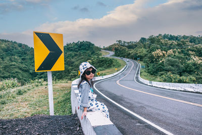 Rear view of woman standing on road against sky