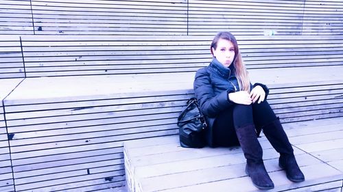 Full length portrait of young woman puckering while sitting