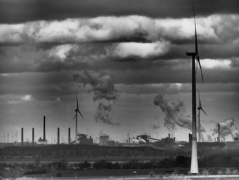 Smoke stacks against cloudy sky