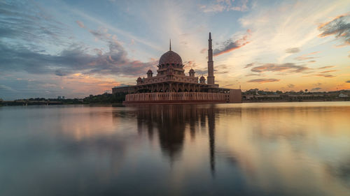 View of mosque by lake against sky at sunset