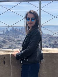 Portrait of beautiful young woman standing against built structure