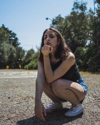 Young woman crouching on road