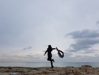 Full length of woman standing on beach against sky