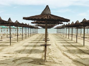 Thatched roofs at beach against sky