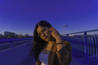 Young woman smiling while standing against blue sky