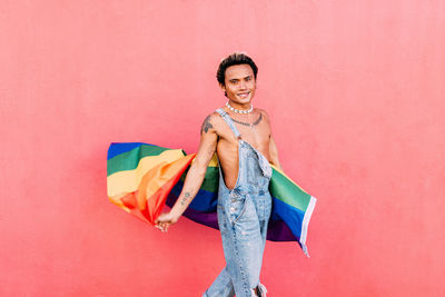 Portrait of young woman standing against yellow background