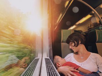 Close-up of woman carrying son sitting in train