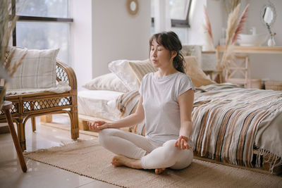 Portrait of young woman sitting on bed at home