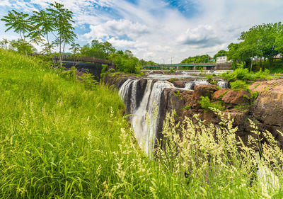 Scenic view of waterfall on field against sky