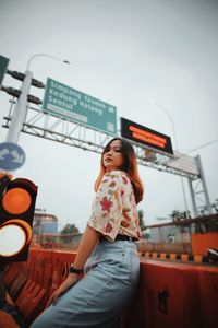 Low angle view of woman looking at camera against sky