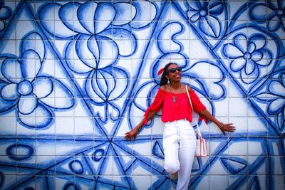 Portrait of a smiling young woman standing against wall