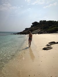 Full length of woman walking at beach against sky