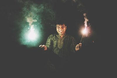 Man holding umbrella while standing against black background