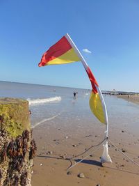 Flag on beach against clear sky