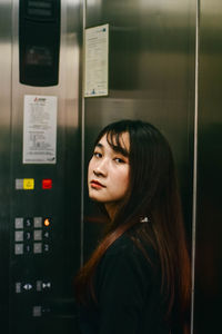 Portrait of young woman standing inside elevator in building