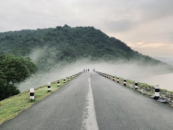 Rear view of people walking on road against sky