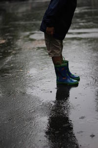 Low section of boy standing on puddle
