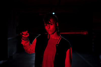 Portrait of young man standing against red curtain