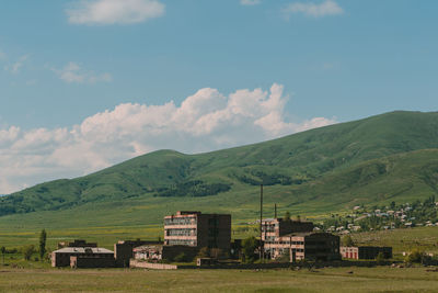 Houses on field by mountains against sky