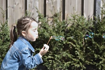 Side view of woman holding plants against trees