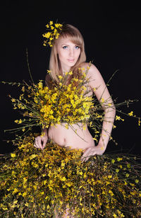 Portrait of woman with yellow flowers against black background