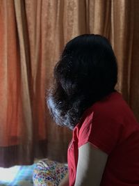 Rear view of woman sitting at home