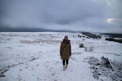 Full length of man standing on snow covered landscape against sky