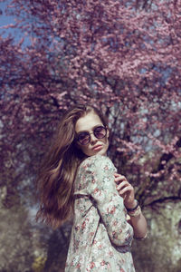 Portrait of a young woman standing near spring blossom tree