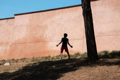 Rear view of man standing on field against wall