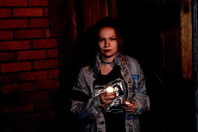 Portrait of woman holding tea light candle at night