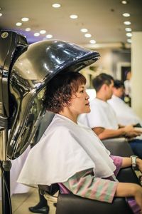 Side view of woman sitting in hair salon 