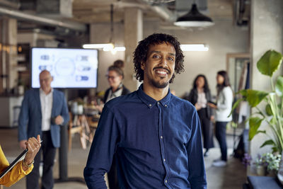 Portrait of smiling businessman standing at creative office